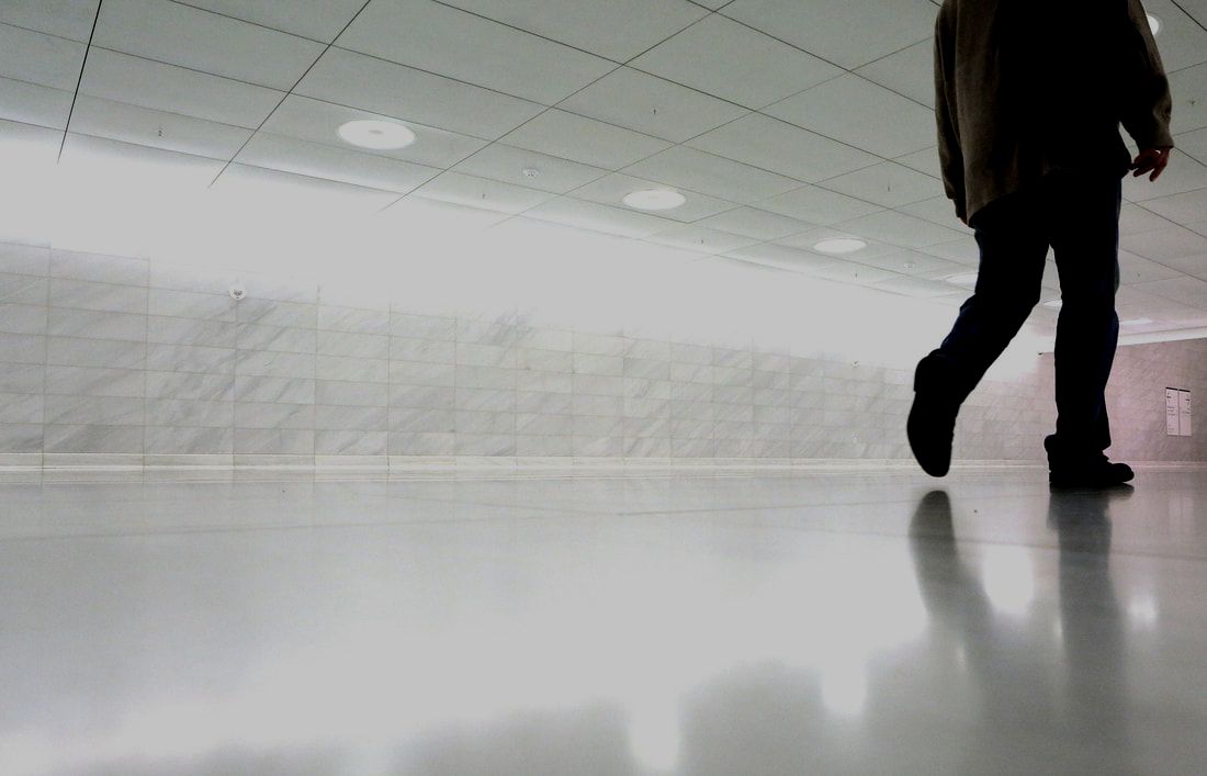 Man wearing dark clothes walking through hallway on bright, white, polished epoxy flooring